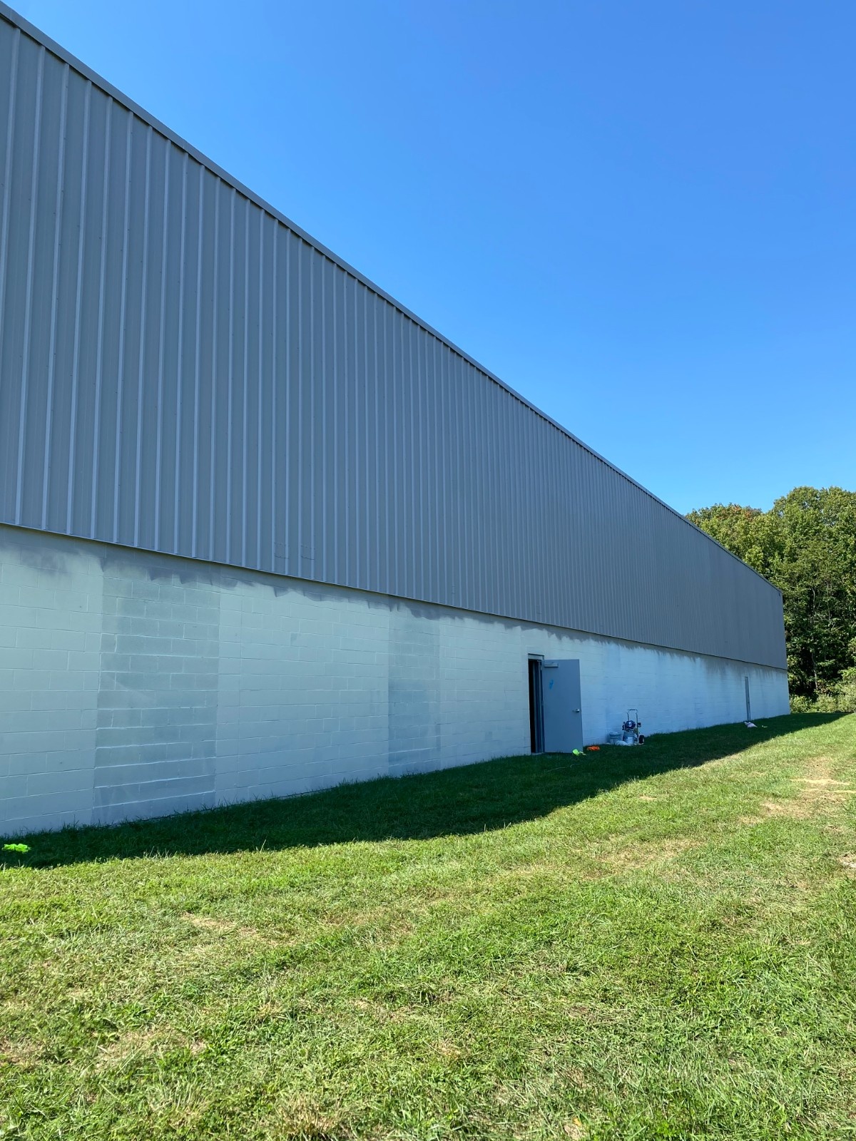 Freshly painted commercial metal building exterior by Texas Pro Painters with crisp light gray coating on block and siding, professional finish in Mount Pleasant, TX.